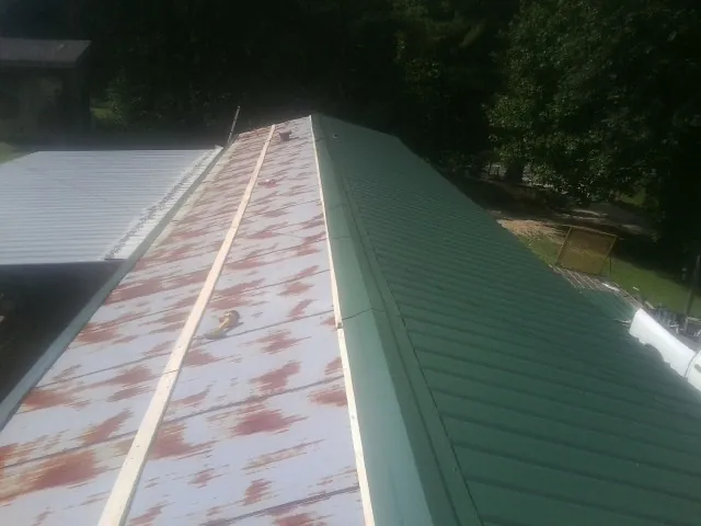 Old rusted panels beside newly installed green metal roofing — Wind Damage Roof Repair by Roofing Brothers in Port Tobacco