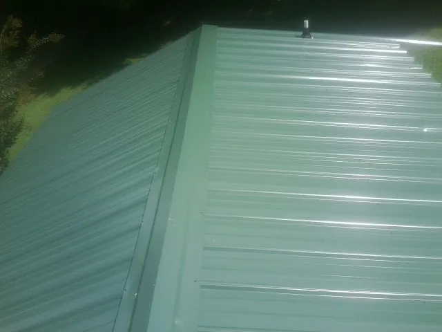 New green metal panels meeting at the ridge of a roof — Flat Roof Repair work by our crew in Port Tobacco