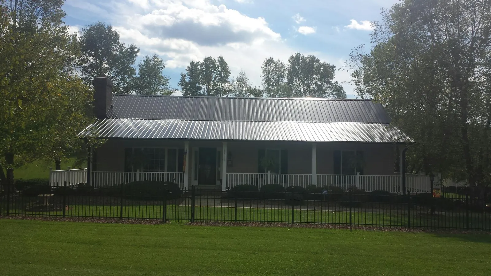 Gray metal roof on a brick ranch with a full width front porch — Gutter Guard Installation work by our crew in Port Tobacco
