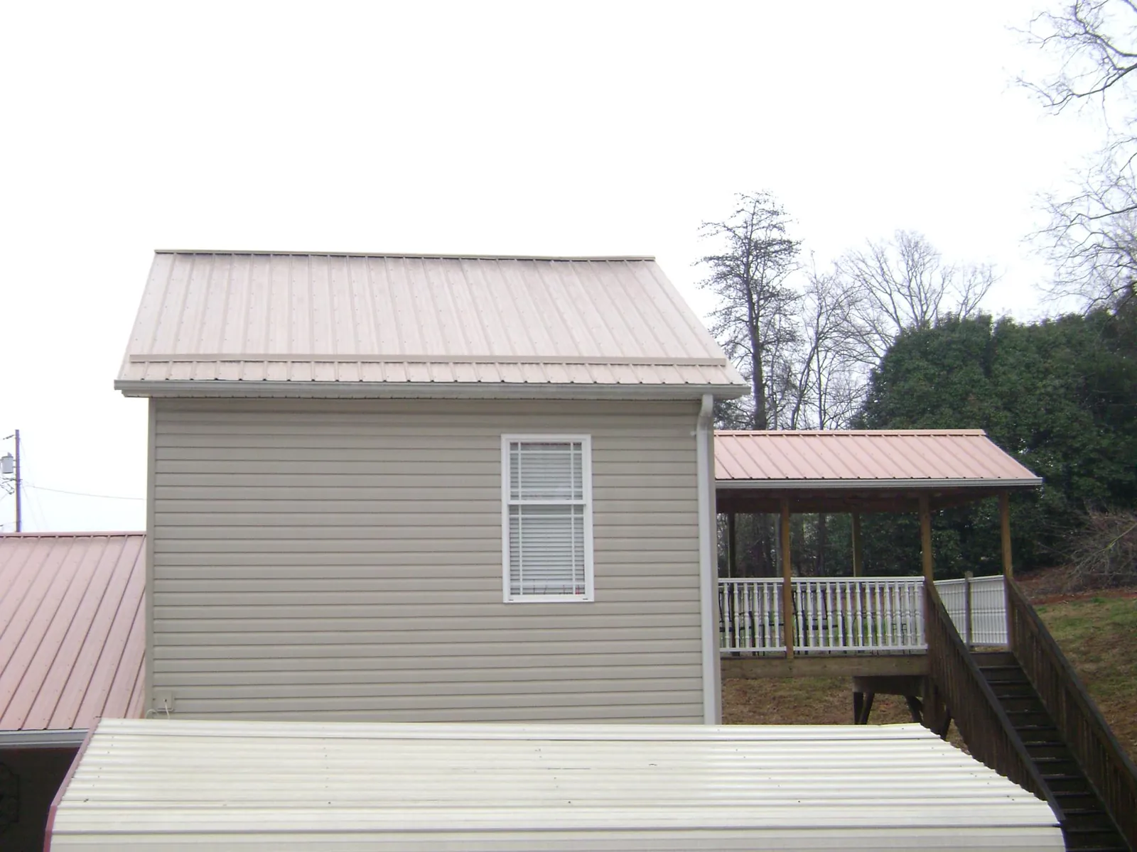 Tan metal roofs on a two story addition and attached porch, from a Roof Replacement job in Port Tobacco